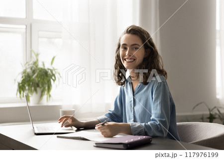 Portrait of motivated student woman sit at desk with laptop Portrait of motivated student woman sit at desk with laptop 117976199