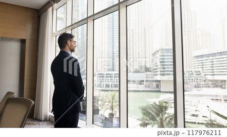 Serious confident business owner man in suit standing at window 117976211