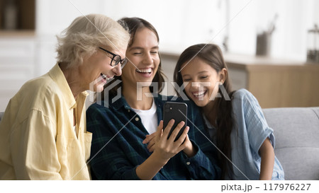 Cheerful girl, young mom and senior granny using funny application Cheerful girl, young mom and senior granny using funny application 117976227