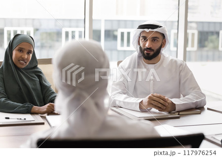 Male and female Arab colleagues talking to partner Male and female Arab colleagues talking to partner 117976254