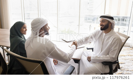 Happy Arabian new company co-owners, partners shaking hands on meeting 117976261