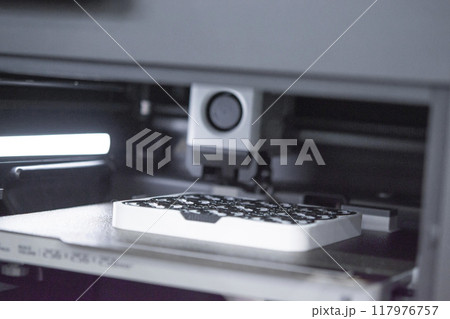 3D printer close up. A working 3D printer in process of printing object from molten plastic. 3D printer creating model by flowing liquid plastic from an extruder of printer. 3D printing technology 3D printer close up. A working 3D printer in process of printing object from molten plastic. 3D printer creating model by flowing liquid plastic from an extruder of printer. 3D printing technology 117976757