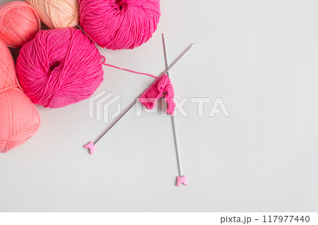 Pink knitted wool on gray background with knitting needles for knitting warm clothes and hobbies needlework 117977440