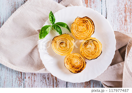 Close up of caramelized roasted onions and basil on a plate on the table top view Close up of caramelized roasted onions and basil on a plate on the table top view 117977487