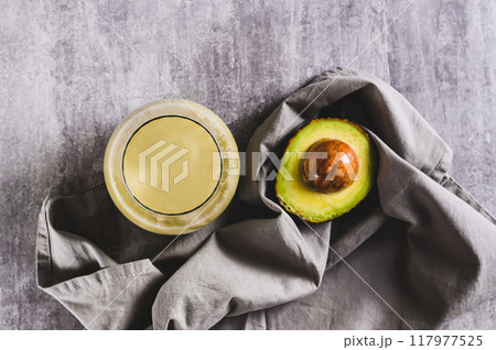 Close up of refreshing avocado and apple smoothie in a glass on the table top view Close up of refreshing avocado and apple smoothie in a glass on the table top view 117977525