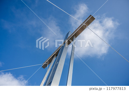 The summit cross stands tall against a backdrop of blue skies and fluffy clouds atop Wildspitze mountain, inviting mountaineers and hikers to admire the breathtaking alpine views. 117977813
