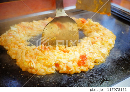 鉄板焼き屋さんでもんじゃ焼きを焼いているところ。 鉄板焼き屋さんでもんじゃ焼きを焼いているところ。 117978151