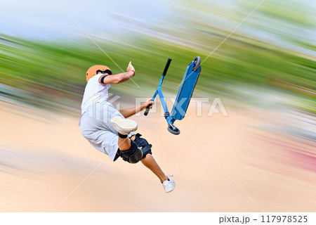 Young man practicing Scootering (Freestyle Scootering) in the new SkatePark in the central park of Igualada, Barcelona, Spain. blurred background 117978525