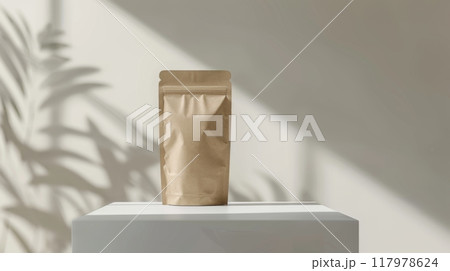 A brown paper bag stands on a white pedestal, bathed in natural light. 117978624