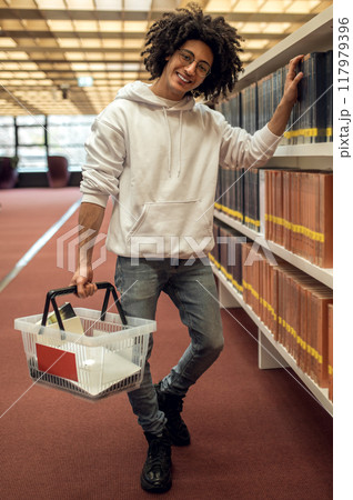 Man student in library reaching for book from shelf preparing for university seminars 117979396
