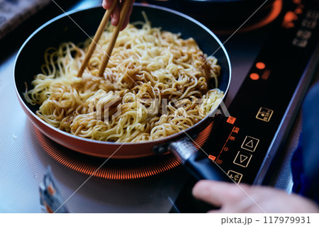 焼きそばの麺を炒める女性の手元 117979931