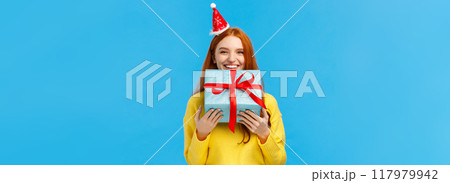 Girl cant wait give sibling her gift, smiling carry cute christmas wrapped present and wearing fancy santa hat, laughing, sharing positive emotions, attend winter holidays party, blue background Girl cant wait give sibling her gift, smiling carry cute christmas wrapped present and wearing fancy santa hat, laughing, sharing positive emotions, attend winter holidays party, blue background 117979942
