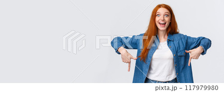 Waist-up portrait happy, lucky redhead girl winning prize, achieve goal in challenge, celebrating, showing people product, looking amused with pretty smile, pointing fingers down, white background 117979980