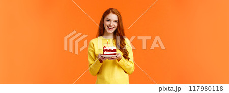 Girlfriend made surprise party, bring piece of cake with one candle to celebrate partner birthday, singing happy b-day and smiling lovely, standing orange background in yellow sweater Girlfriend made surprise party, bring piece of cake with one candle to celebrate partner birthday, singing happy b-day and smiling lovely, standing orange background in yellow sweater 117980118