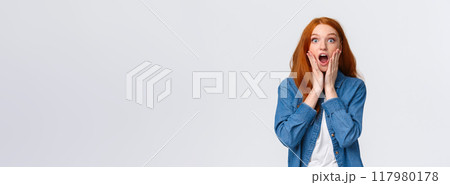 Oh my gosh, amazing. Surprised speechless redhead woman standing starled and shocked, touch face, drop jaw and stare camera fascinated, got job, won prize, standing white background 117980178