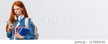 Displeased, mad or confused good-looking redhead college girl, student with backpack, notebooks and headphones, reading strange message on smartphone, frowning upset, white background Displeased, mad or confused good-looking redhead college girl, student with backpack, notebooks and headphones, reading strange message on smartphone, frowning upset, white background 117980182