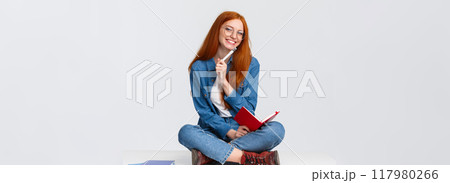 Charismatic, friendly cute redhead girl dreaming, taking notes or prepare homework while sitting on floor with legs crossed, holding notebook and pen, writing over white background Charismatic, friendly cute redhead girl dreaming, taking notes or prepare homework while sitting on floor with legs crossed, holding notebook and pen, writing over white background 117980266