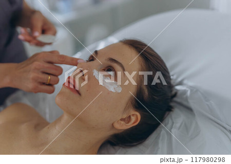 A professional beautician injects Botox into the face of a young woman A professional beautician injects Botox into the face of a young woman 117980298