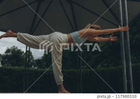 young woman athlete in sportswear practices yoga, enjoys training 117980310