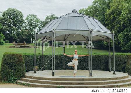 young woman athlete in sportswear practices yoga, enjoys training young woman athlete in sportswear practices yoga, enjoys training 117980322