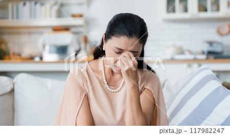 Upset Asian senior woman sitting on sofa Upset Asian senior woman sitting on sofa 117982247