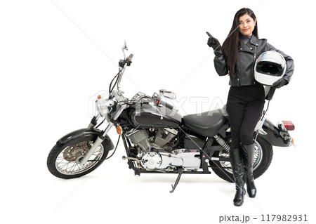 バイクの横に立って、ヘルメットを持って、指差しするバイク女子 バイクの横に立って、ヘルメットを持って、指差しするバイク女子 117982931