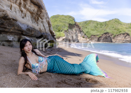 夏の海辺の砂浜に寝そべる若い女性の人魚 117982938
