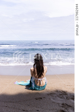 海を見て砂浜に座る若い女性の人魚 117982944