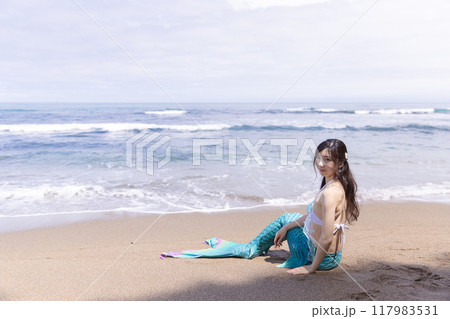 夏の海辺の砂浜に座って微笑む若い女性の人魚 117983531