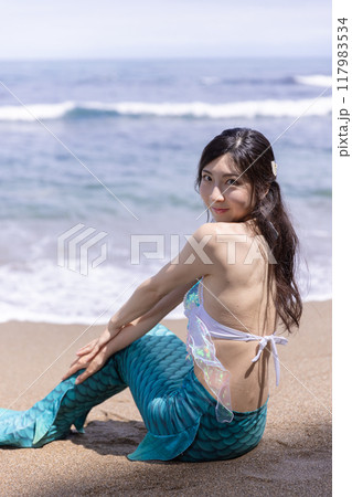 海辺の砂浜に座る若い女性の人魚 117983534