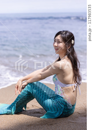 海辺の砂浜に座る若い女性の人魚 117983535