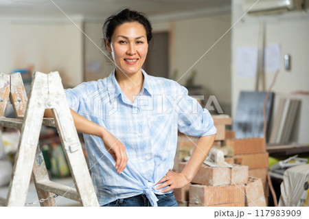 Portrait of satisfied asian woman against the backdrop of renovated room in cottage 117983909
