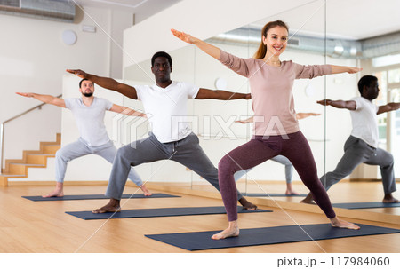 Woman and men practising warrior II pose 117984060
