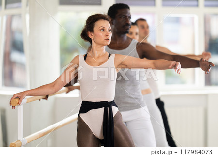 Group of dancers practicing develope at barre Group of dancers practicing develope at barre 117984073