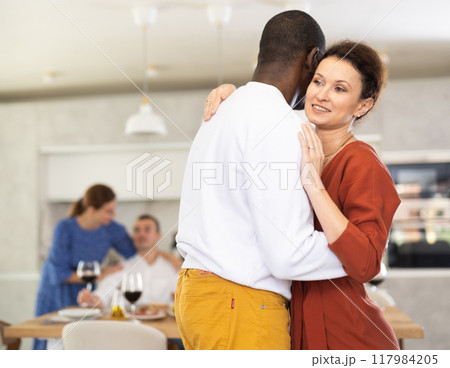 Friends party - men and women of different nationalities dancing slow dance at home 117984205