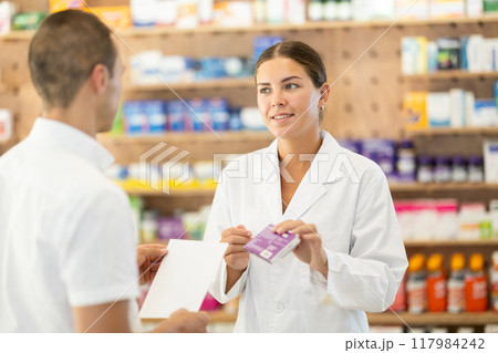 Female pharmacist consulting young guy about medicament according to recipe 117984242