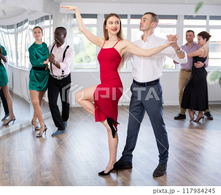 Woman enjoying passionate Latin American dancing with male partner in dance hall Woman enjoying passionate Latin American dancing with male partner in dance hall 117984245