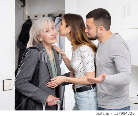 Young family couple seeing off mature woman Young family couple seeing off mature woman 117984328