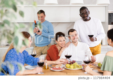 Multiethnic women and men friends chatting and drinking 117984404