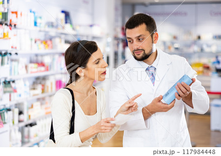 Apothecary giving advise about medicine to woman Apothecary giving advise about medicine to woman 117984448
