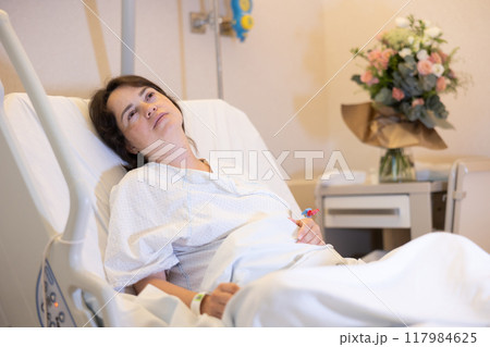 Female patient recovering after surgery in comfortable hospital room 117984625