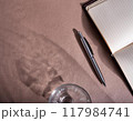 水の入ったコップの影とノートとペン 117984741