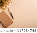 ミモザが飾られたベージュの背景に置かれたノートとペン 117984748