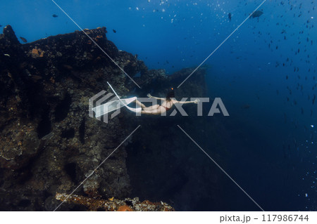 Sporty female freediver swims underwater and explores old wreck ship in Tulamben, Bali. Sporty female freediver swims underwater and explores old wreck ship in Tulamben, Bali. 117986744