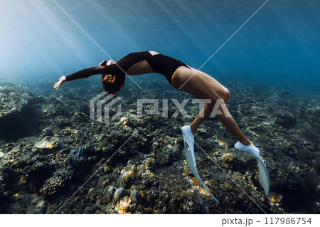 Freediver woman posing over coral reef with sun rays in tropical ocean 117986754