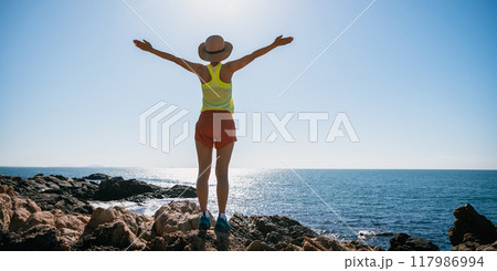 Woman stand on sunrise seaside rocks Woman stand on sunrise seaside rocks 117986994