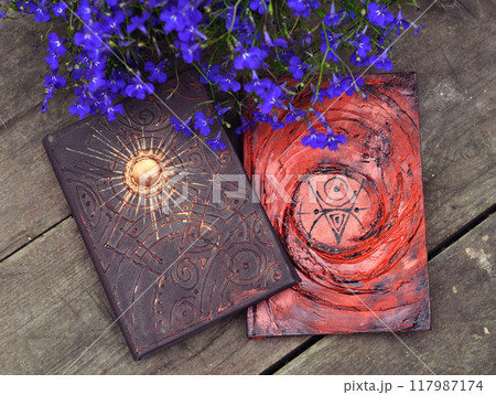 Mystic still life with magic book of spells and flowers on old wooden table. Occult, esoteric, wicca and divination background. Reading and knowledge concept 117987174