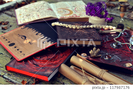 Mystic still life with magic book of spells, old manuscripts and witchy ritual objects on old table. Occult, esoteric, wicca and divination concept. No foreign language, all symbols are fictional 117987176