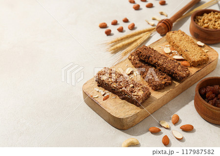 Granola bars on a wooden board with ears of corn and nuts Granola bars on a wooden board with ears of corn and nuts 117987582