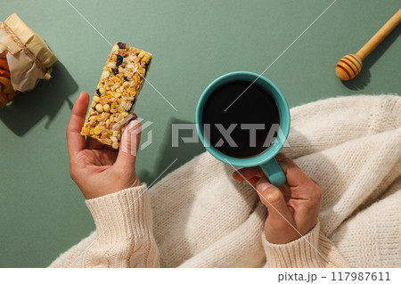 Granola bar with cup of tea in female hands 117987611
